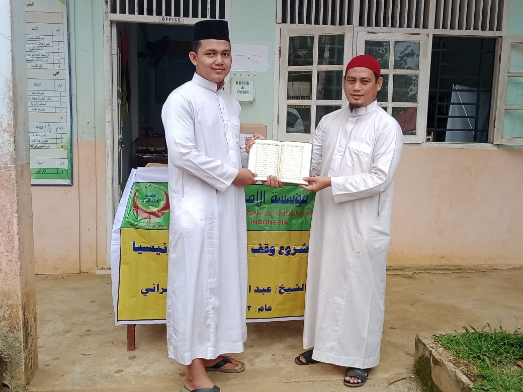 رجلان يعرضان مصحفا أمام مدخل مبنى