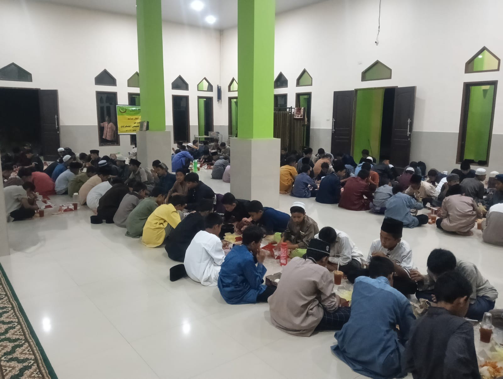صفوف مشاركين يجلسون حول الطعام قرب جدران خضراء وبيضاء