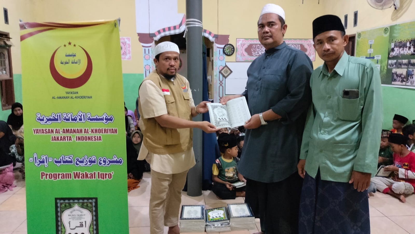 Participants hand over books beside a programme banner.