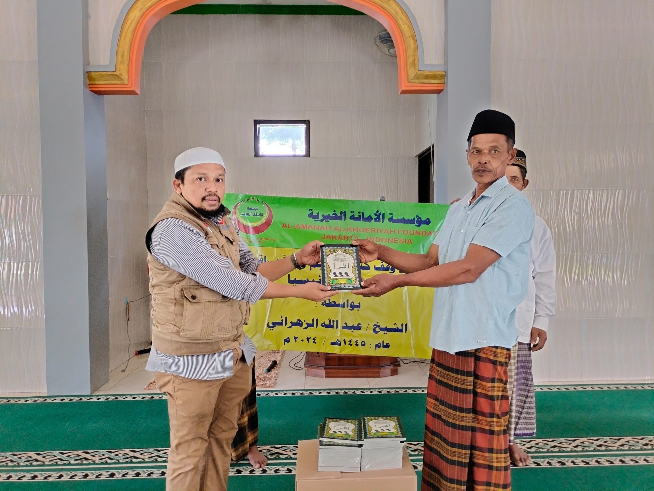 رجلان يعرضان كتاب اقرأ أمام لافتة داخل مسجد