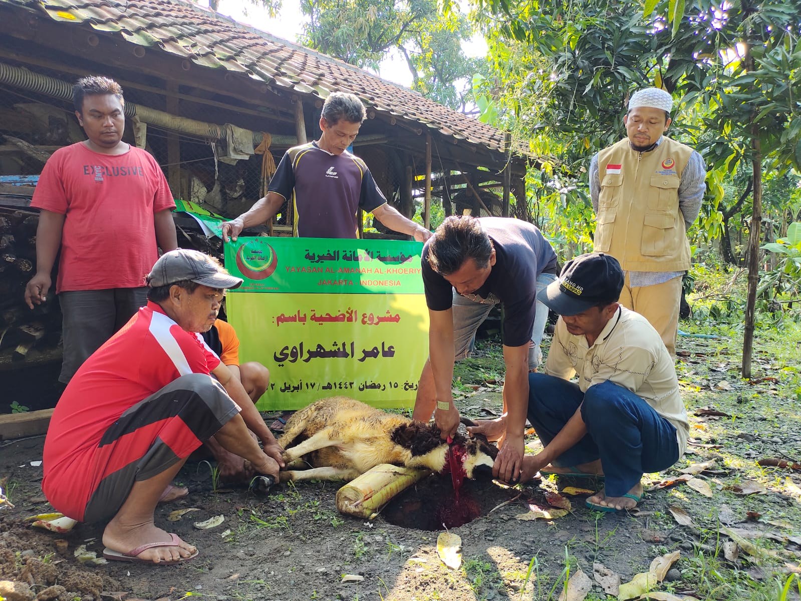 Participants carry out Qurban slaughter beside the programme banner.