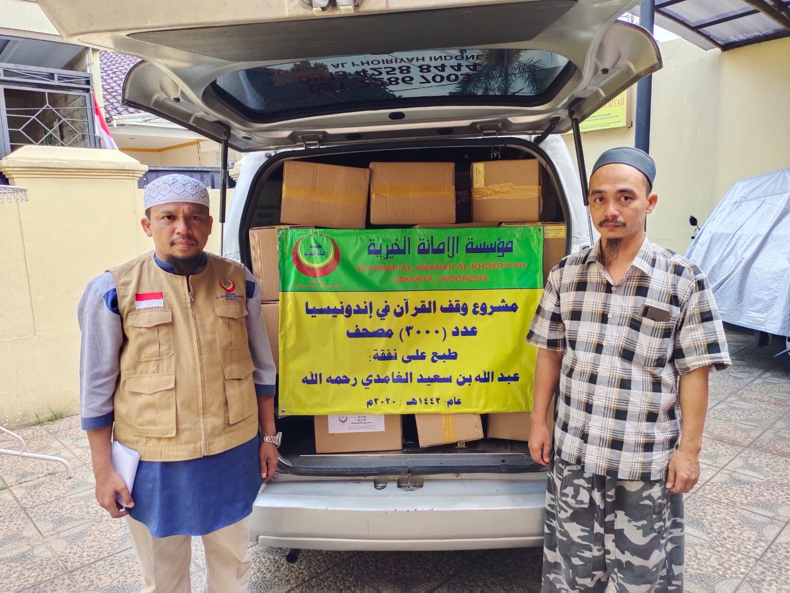 رجلان يحملان لافتة أمام صندوق سيارة محمل بصناديق