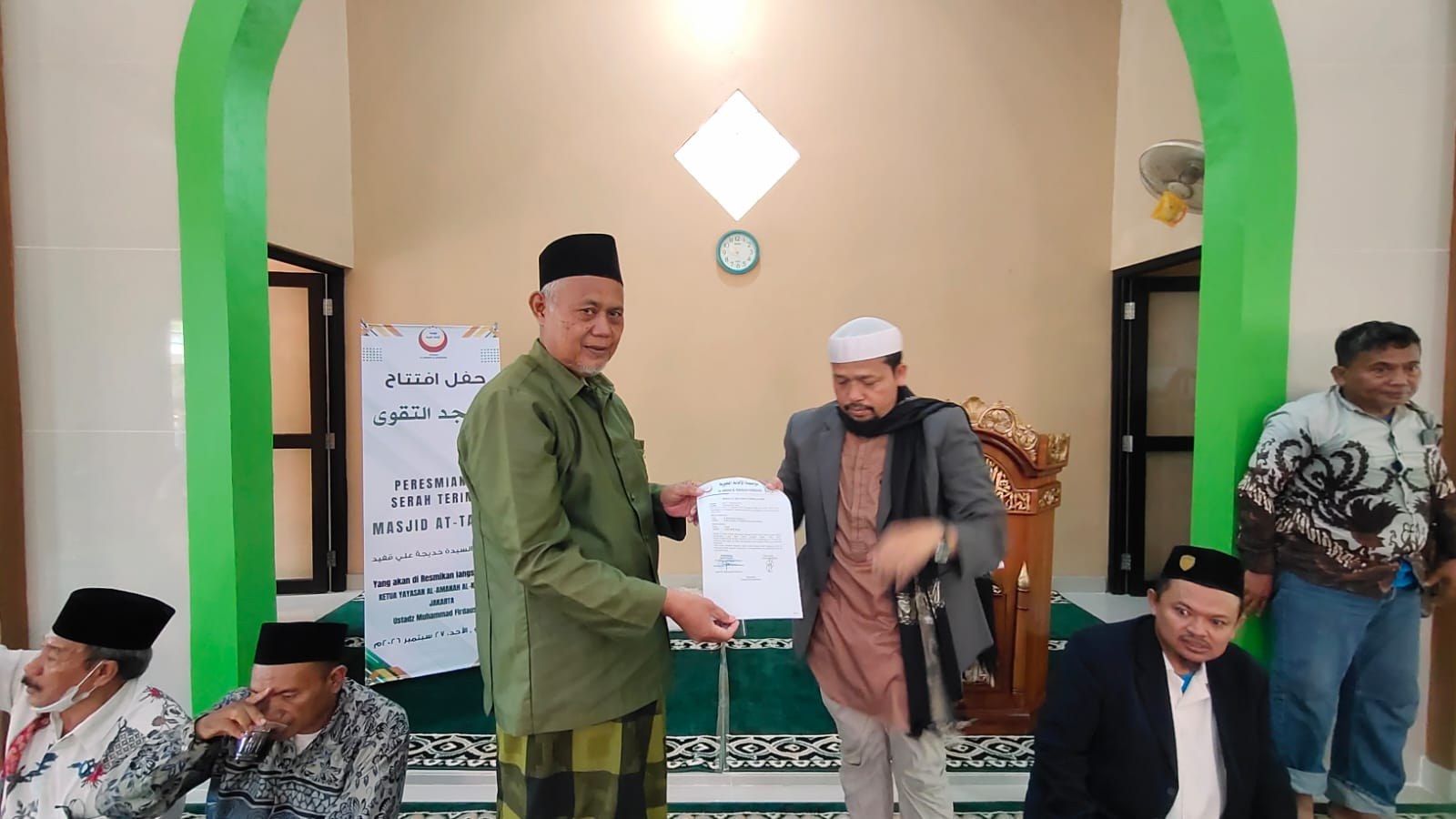 Participants exchange a gift during the mosque inauguration gathering.