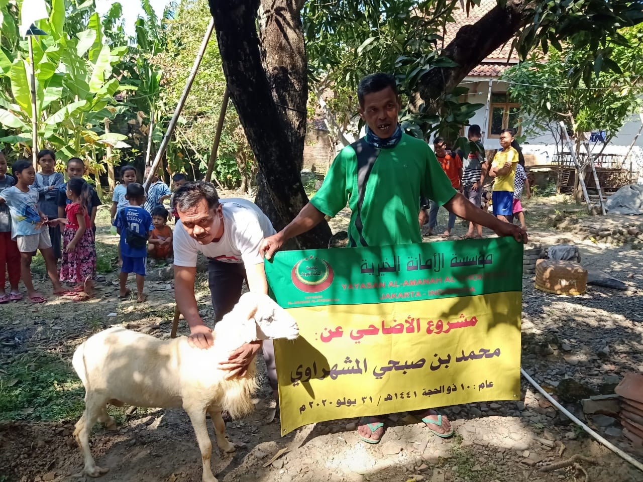 Participants pose with livestock beside the Qurban programme banner.